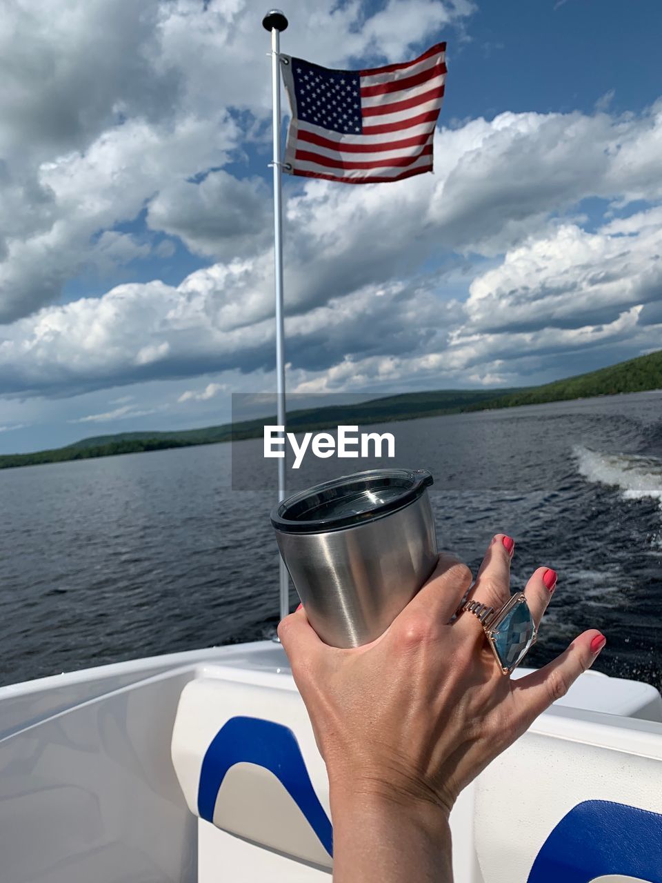 MIDSECTION OF PERSON HOLDING FLAG AGAINST SEA