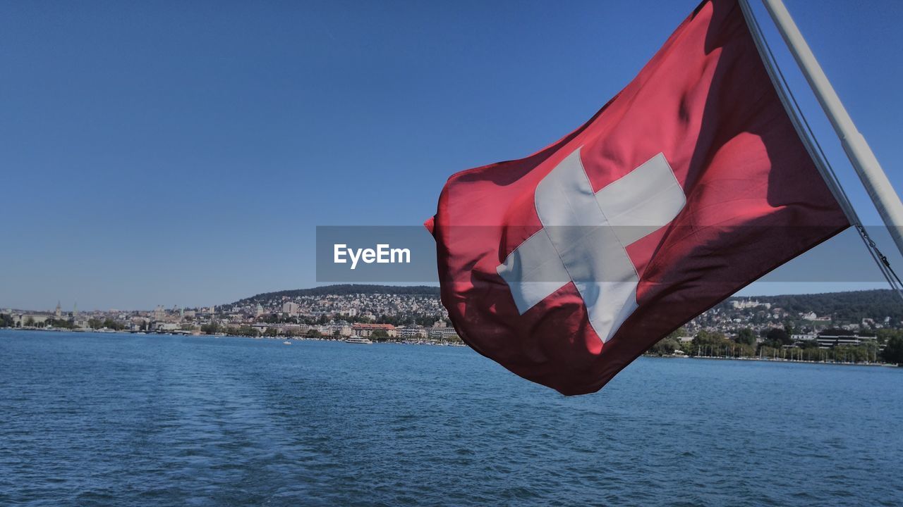 Swiss flag hanging over sea against sky