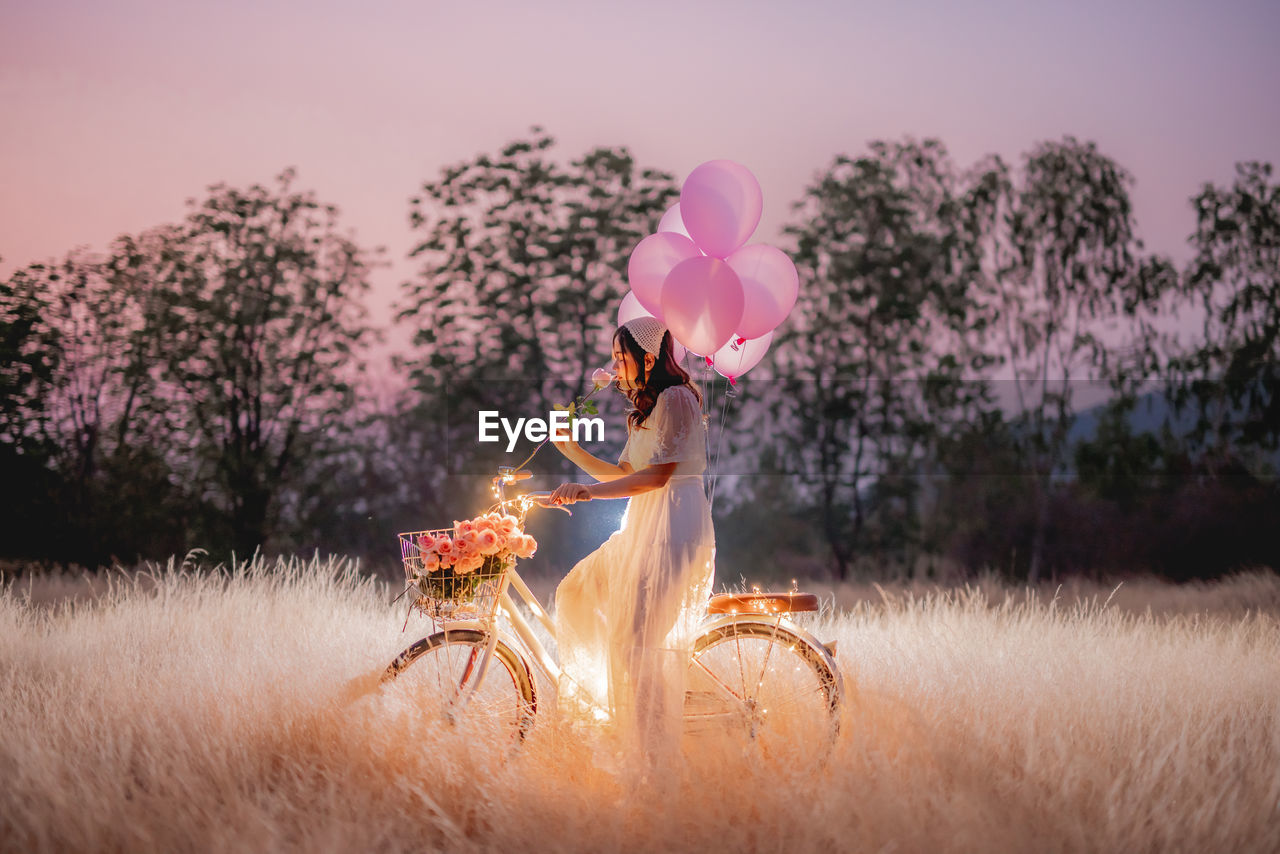 PERSON HOLDING PINK FLOWERS ON FIELD