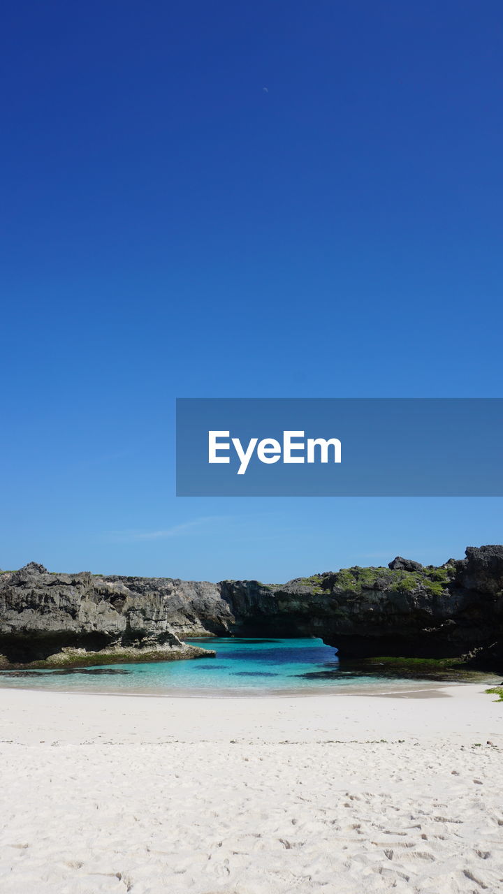 Scenic view of beach against clear blue sky