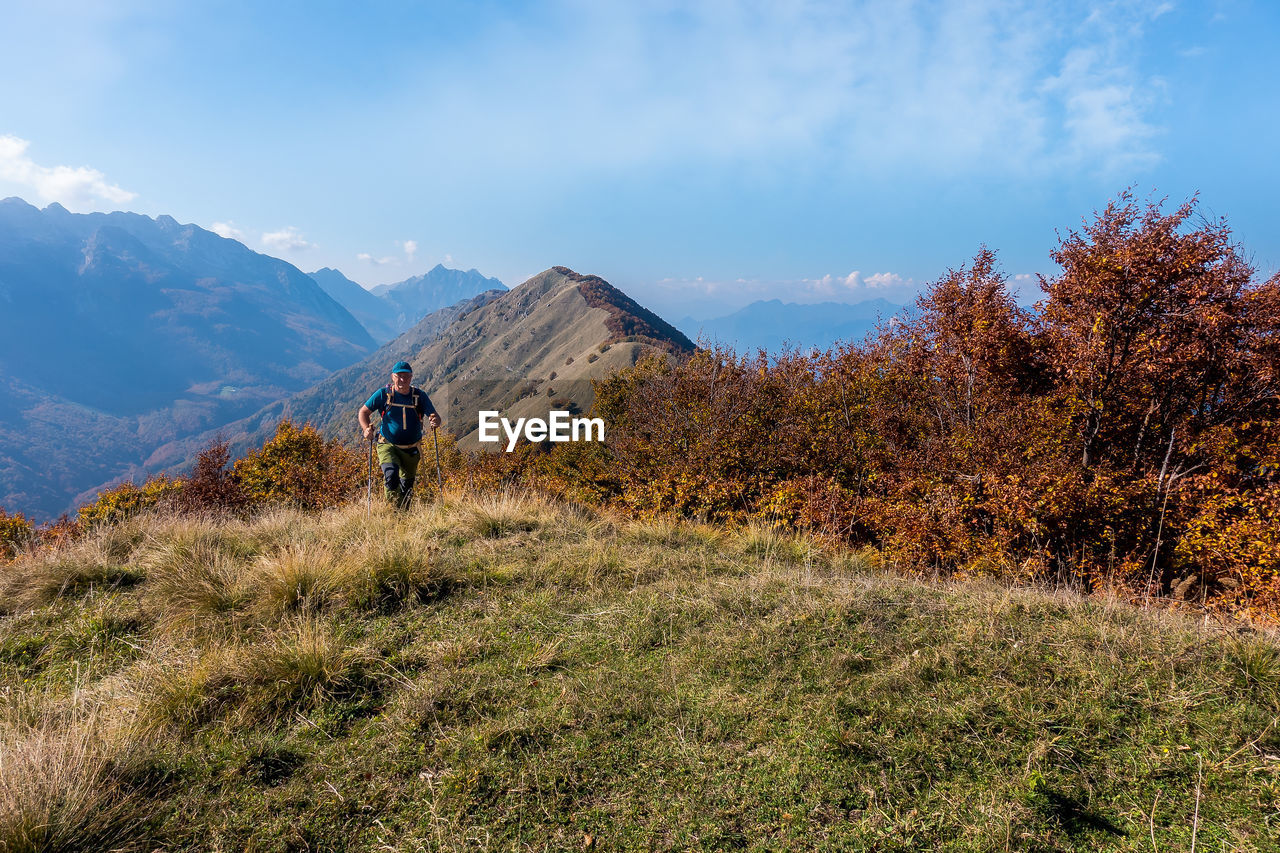 Man walking on grass against mountains and sky