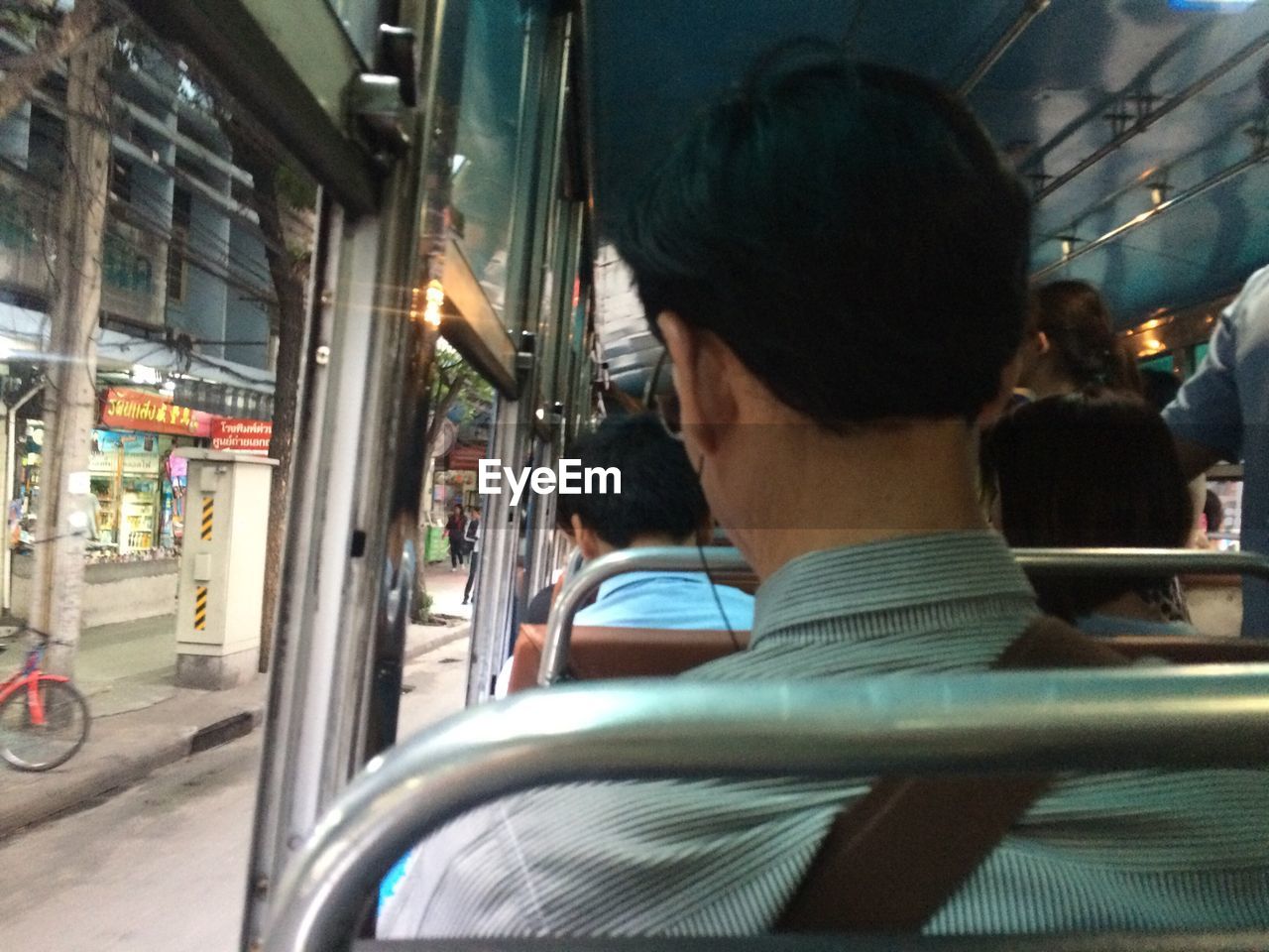 REAR VIEW OF MAN TRAVELING IN BUS