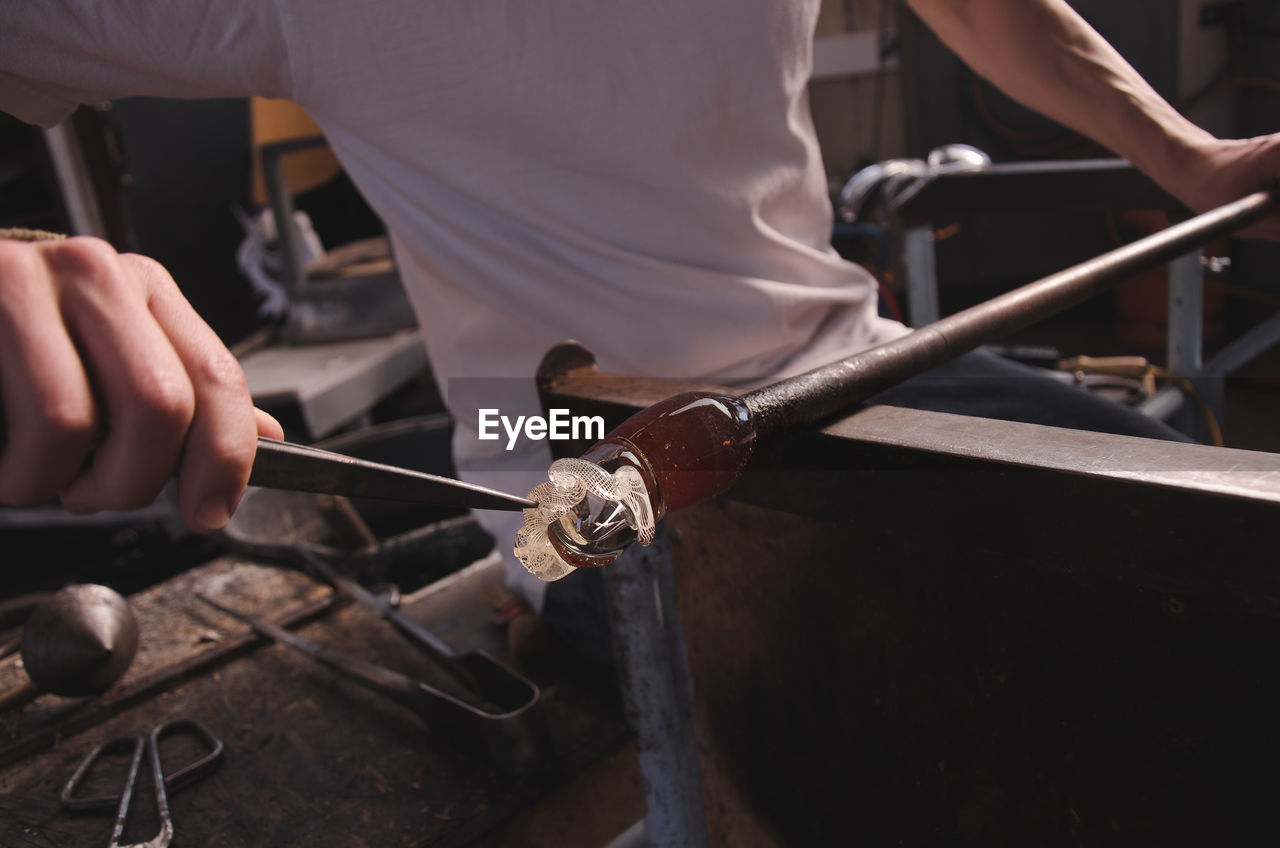 Close-up of man working in glass factory