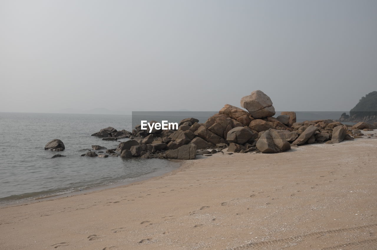 Scenic view of rocks on beach against clear sky