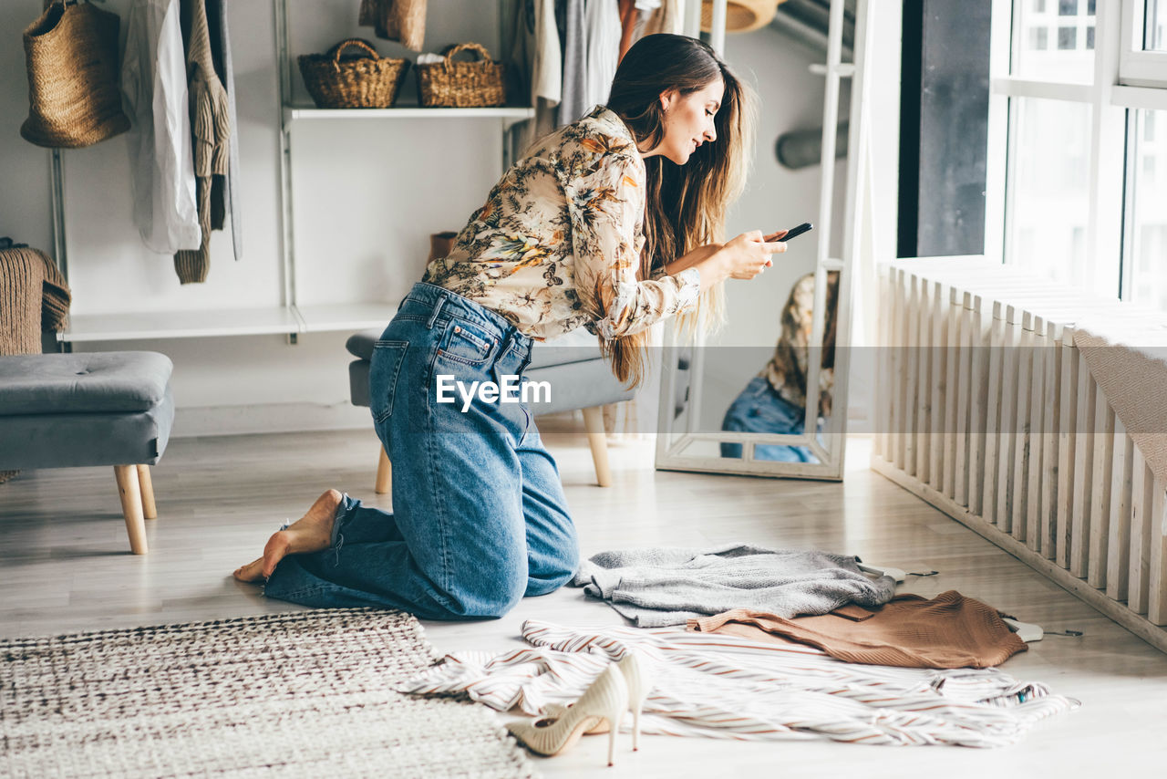 Full length of woman photographing clothes on ground