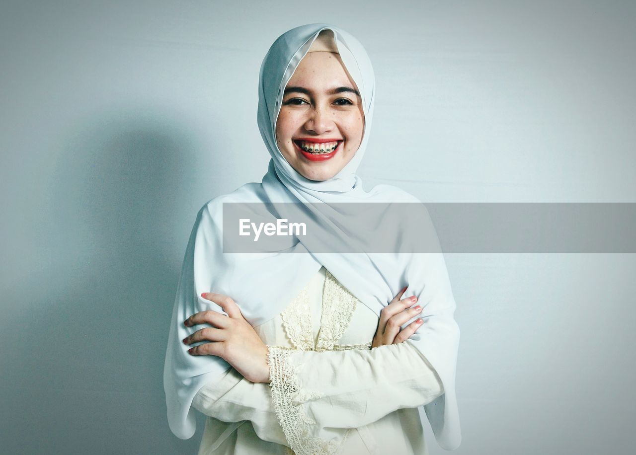 Portrait of smiling young woman in hijab against white background