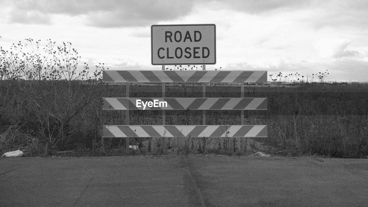 Road closed sign against sky