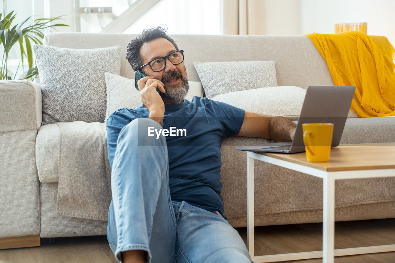 young woman using laptop while sitting on sofa at home