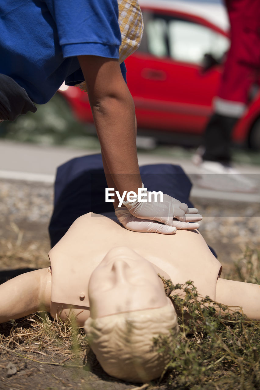 Midsection of man practicing cpr on dummy on field