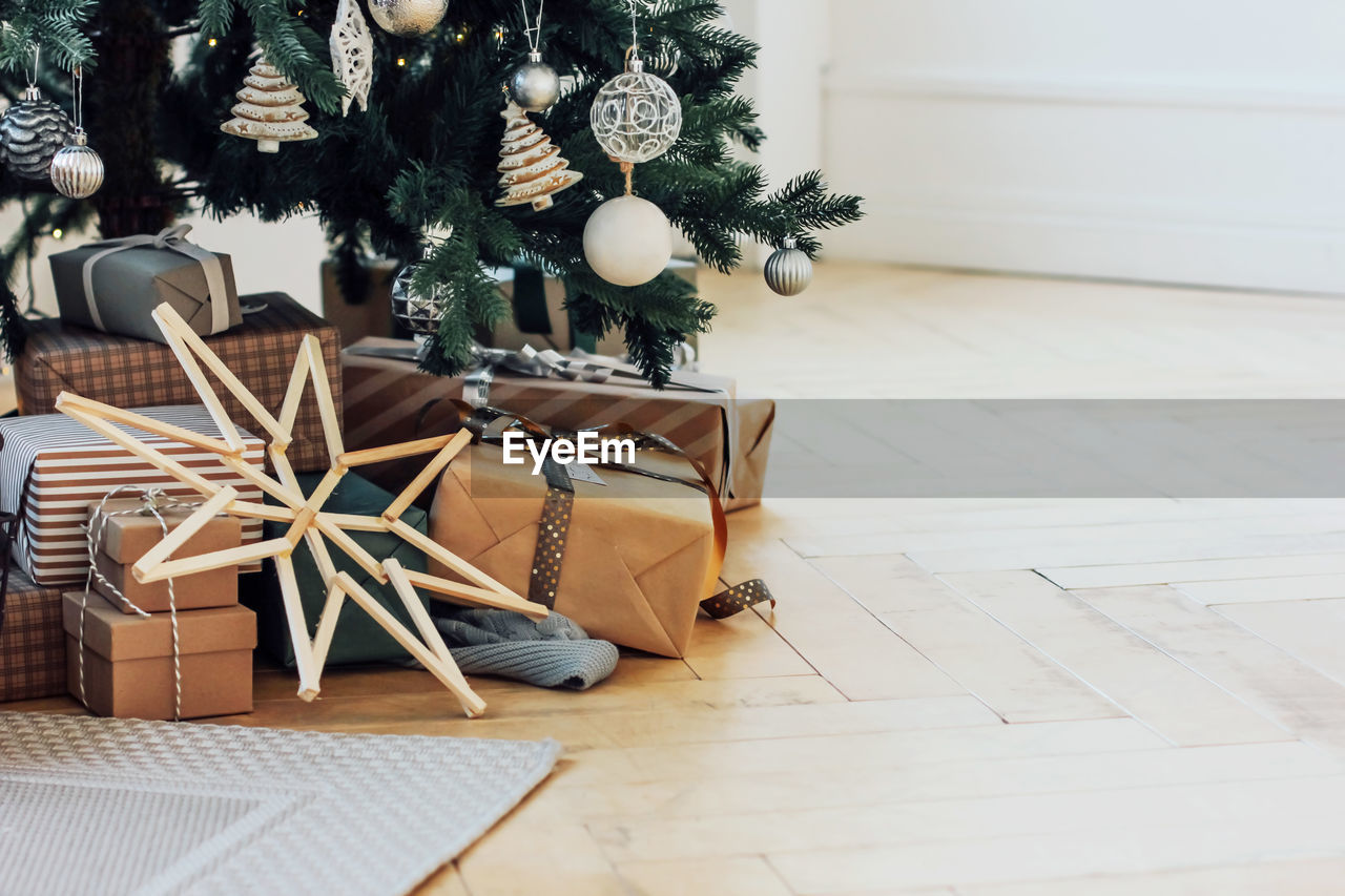 Christmas tree by gifts on hardwood floor at home