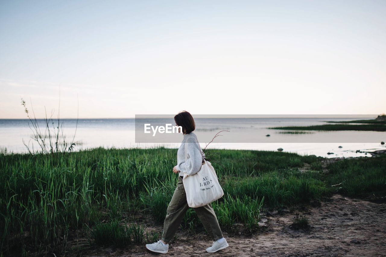 REAR VIEW OF MAN LOOKING AT SEA AGAINST CLEAR SKY