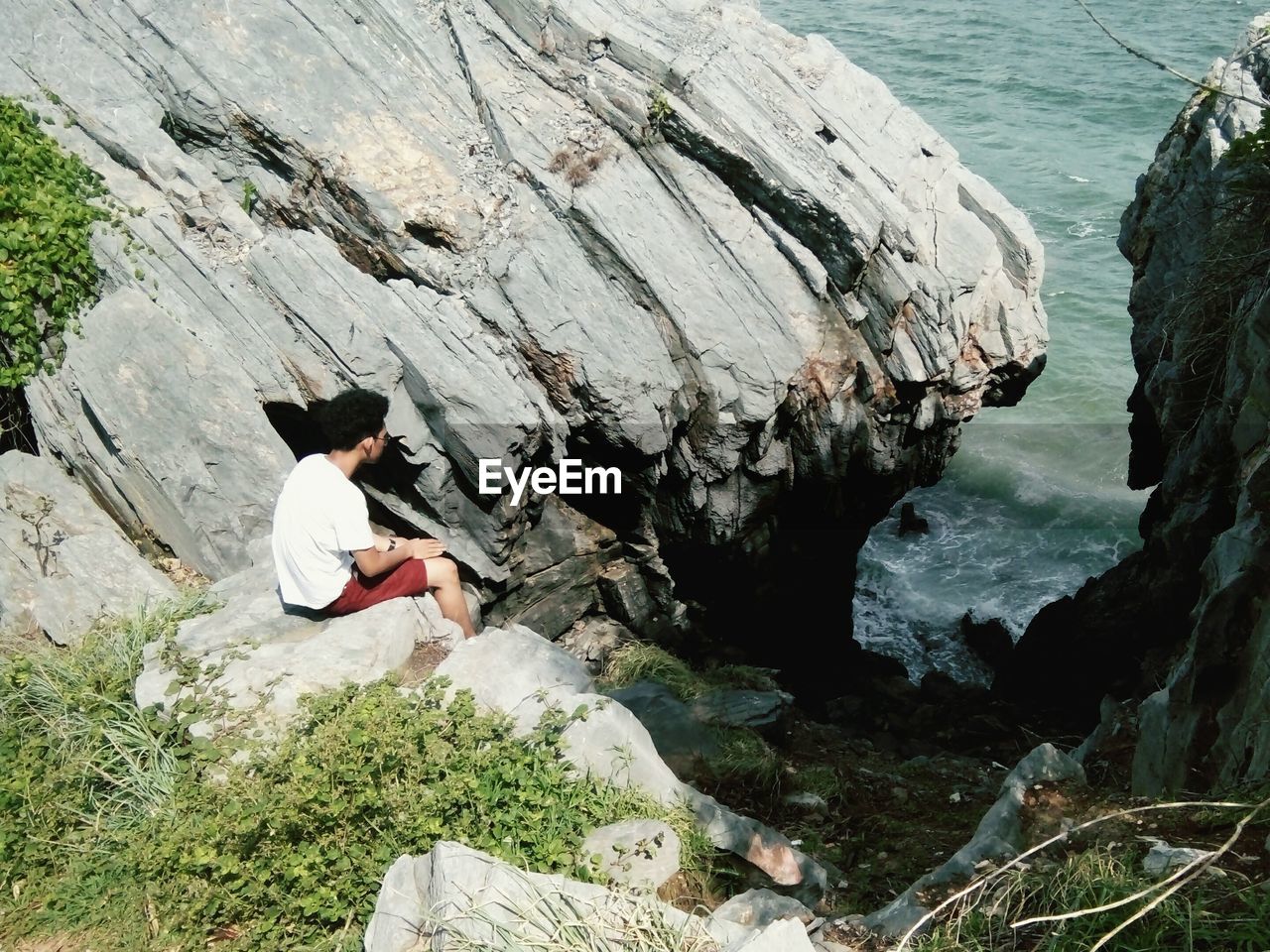 High angle view of man sitting on rocks by sea