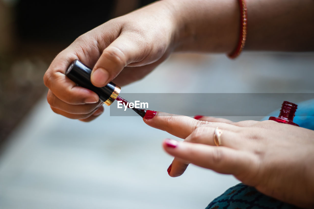 Young girl doing nail polish on nails at day in details