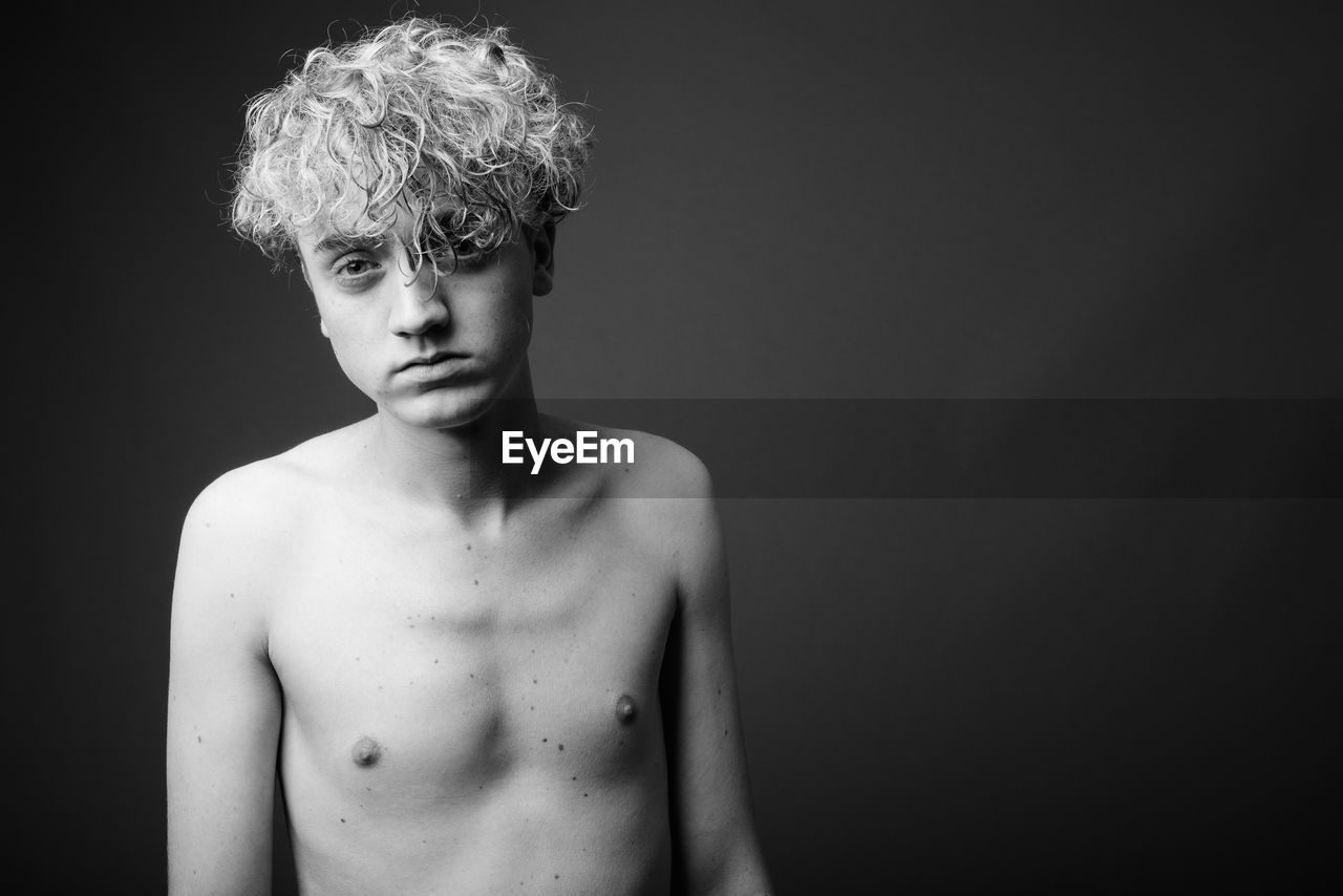 Portrait of shirtless boy against black background