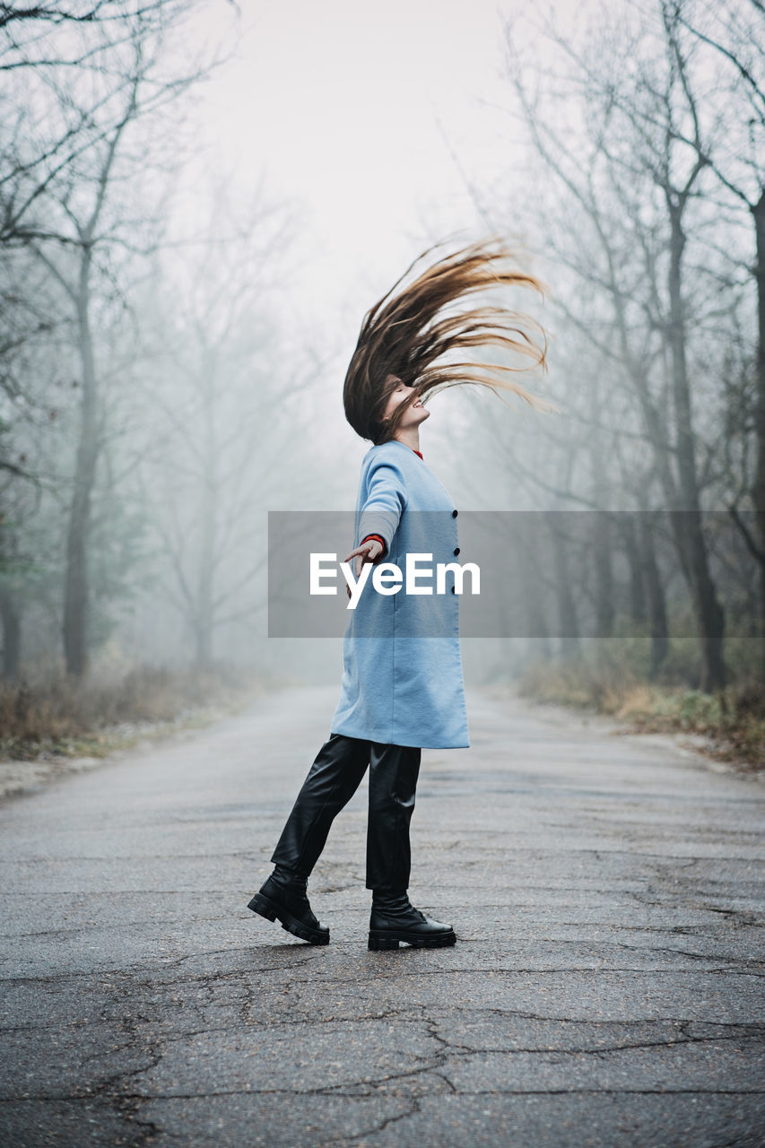 Alone young woman with long fluttering hair express emotions in forest