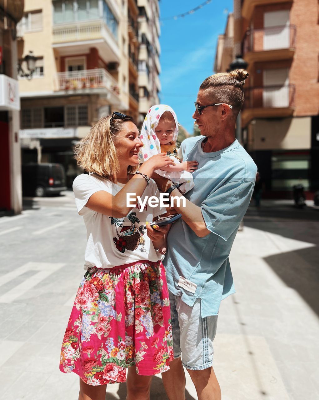 Side view of young family with baby boy standing in city