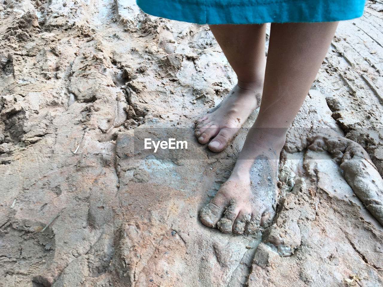 Low section of child standing in mud