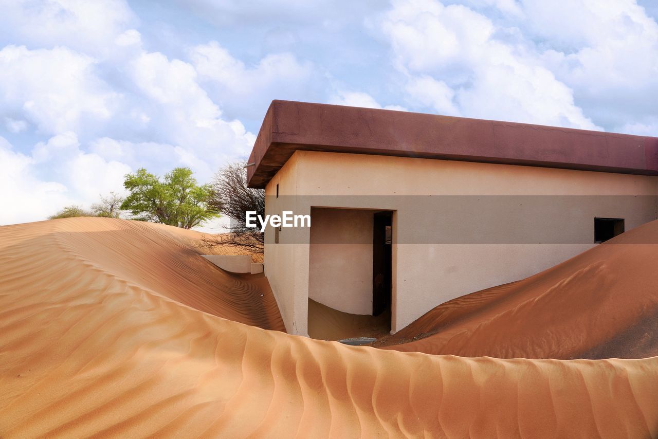 House on sand dune against sky