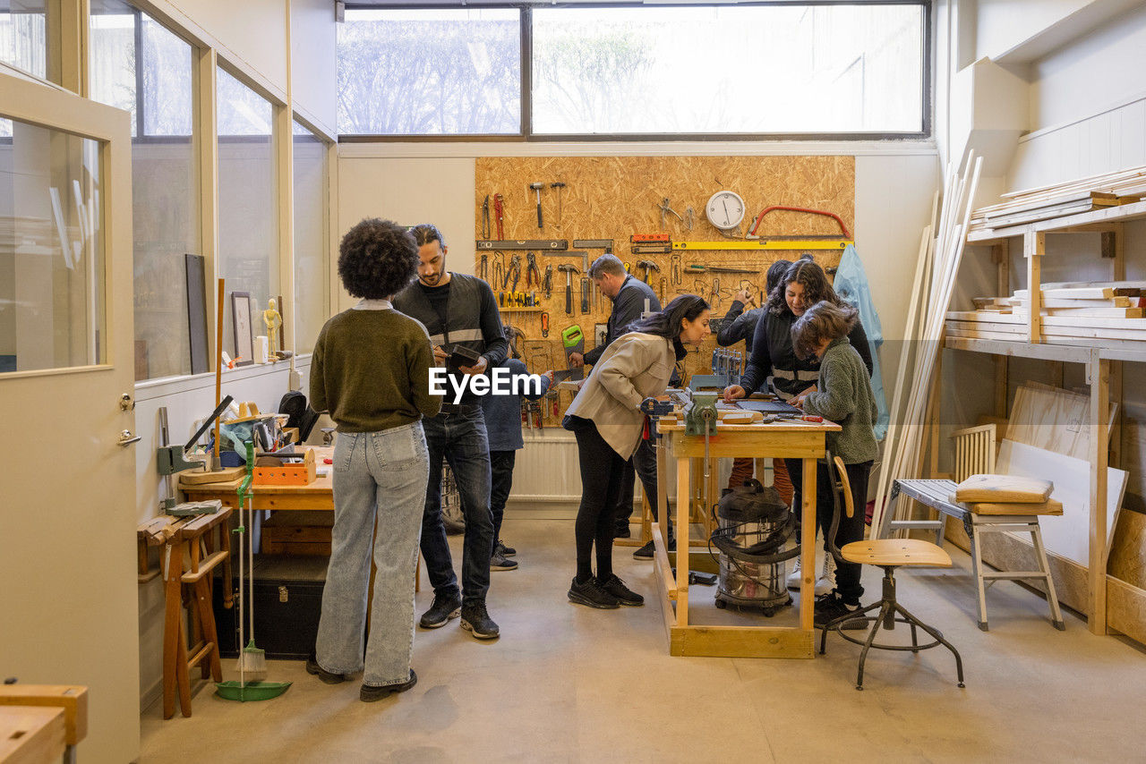 Customers and workers in electronic repair workshop at recycling center