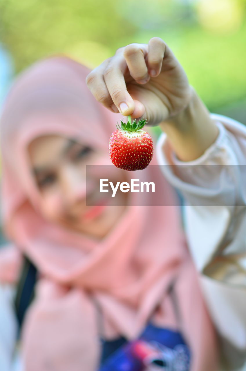 Midsection of woman holding strawberry