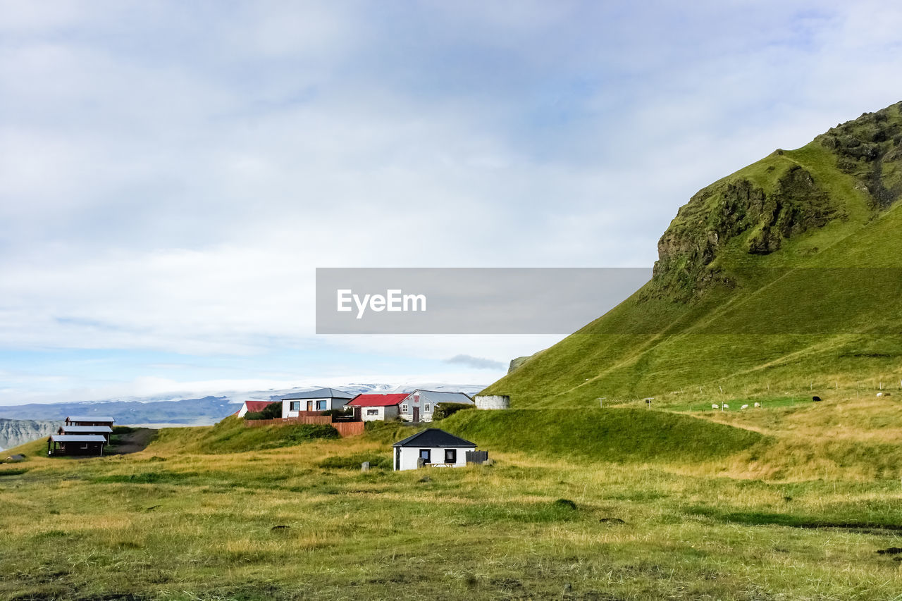 HOUSES ON FIELD AGAINST SKY