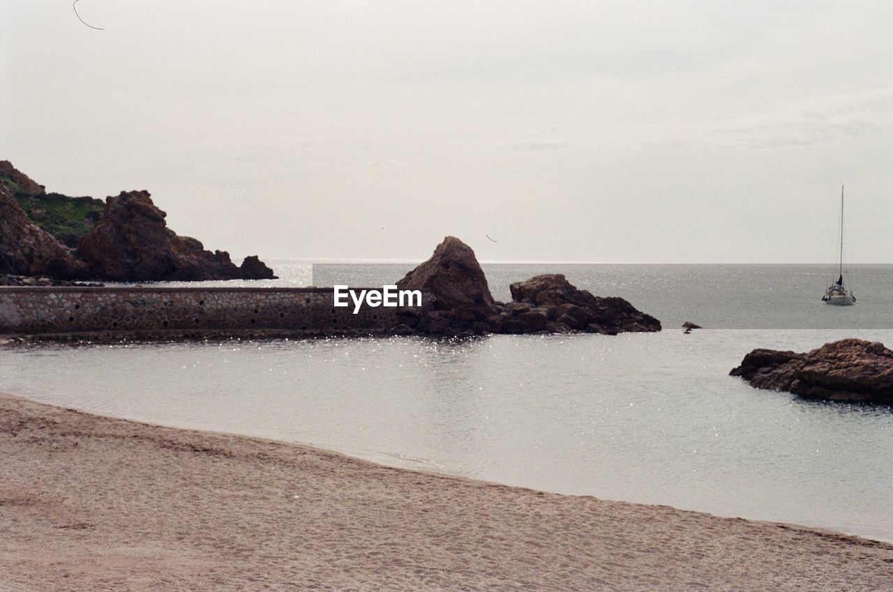 Rock formation on beach and sea against sky