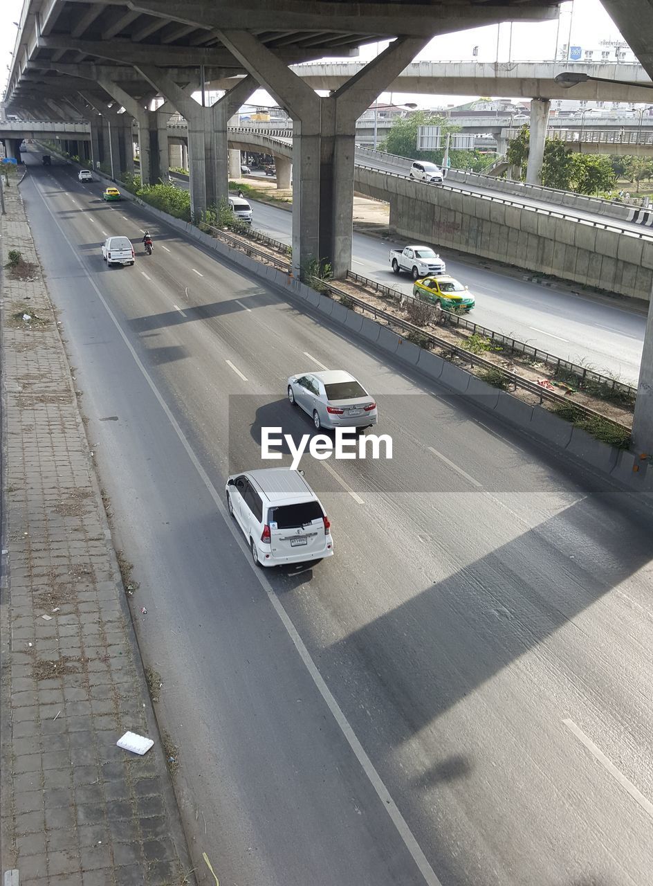 CARS ON ROAD BY BRIDGE IN CITY