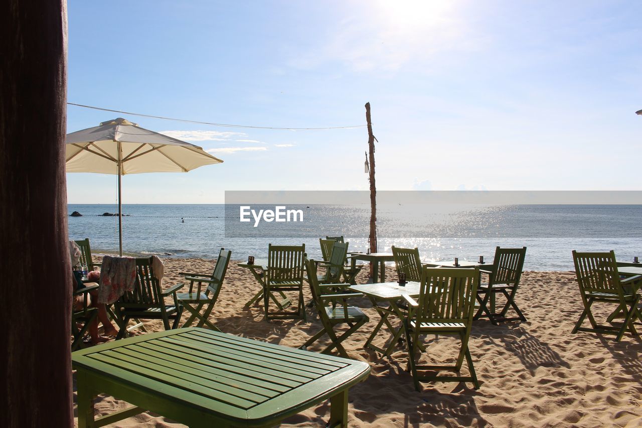 DECK CHAIRS AND TABLE ON BEACH AGAINST SKY