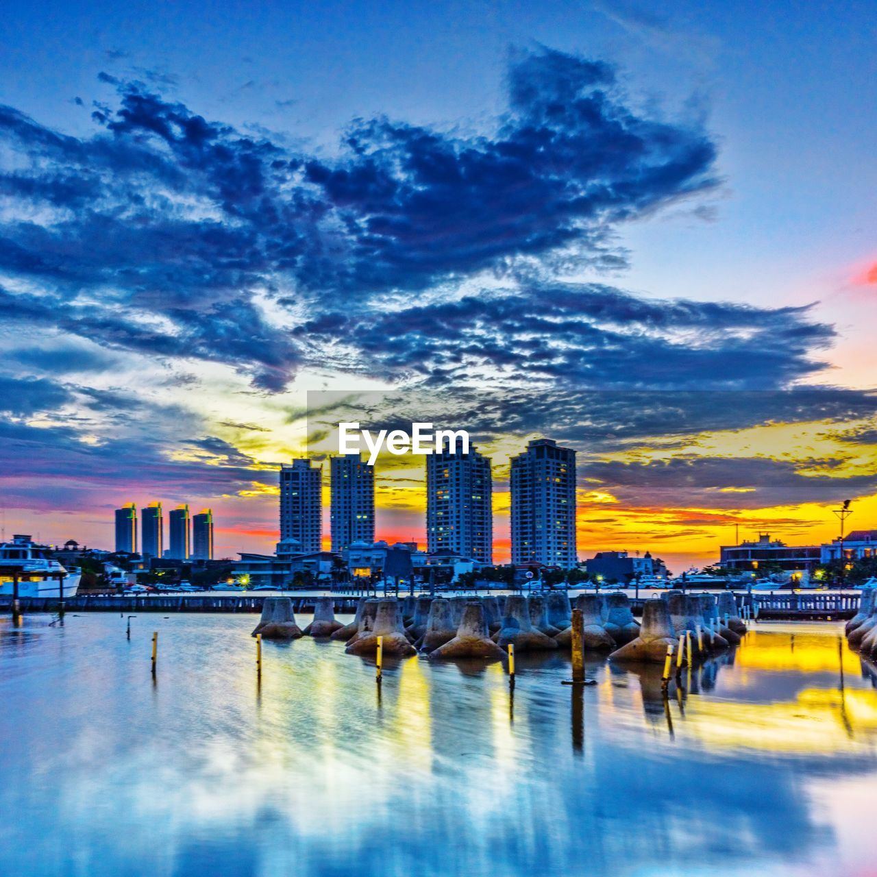 City at waterfront against cloudy sky