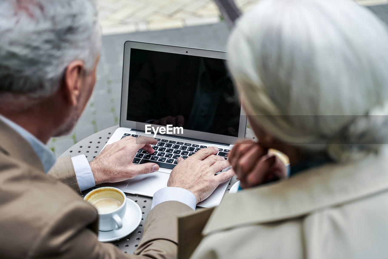 Rear view of man and woman using mobile phone