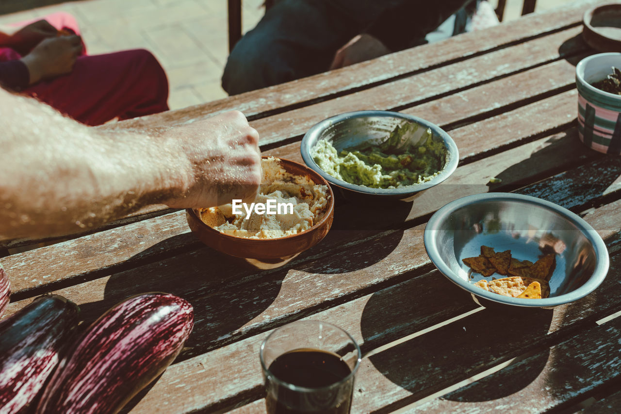 Cropped hand of man holding food on wooden table