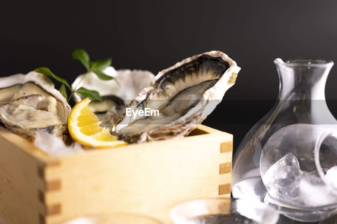 food and drink, food, oyster, citrus fruit, healthy eating, container, freshness, lemon, indoors, no people, fruit, studio shot, animal, wellbeing, drink, seafood, still life, close-up, nature, black background, refreshment, table, glass, still life photography, household equipment