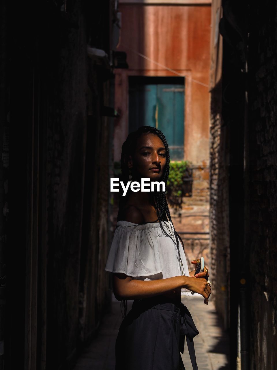 Side view of young woman standing in alley