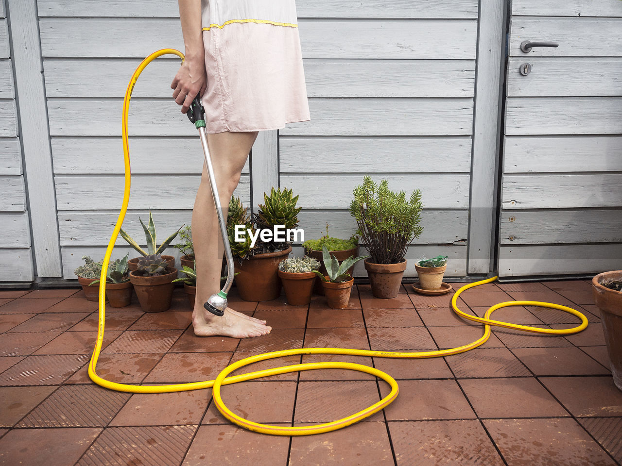 Low section of woman holding hose in balcony