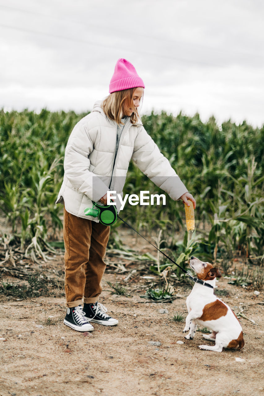 Full length of woman holding leash of dog at farm