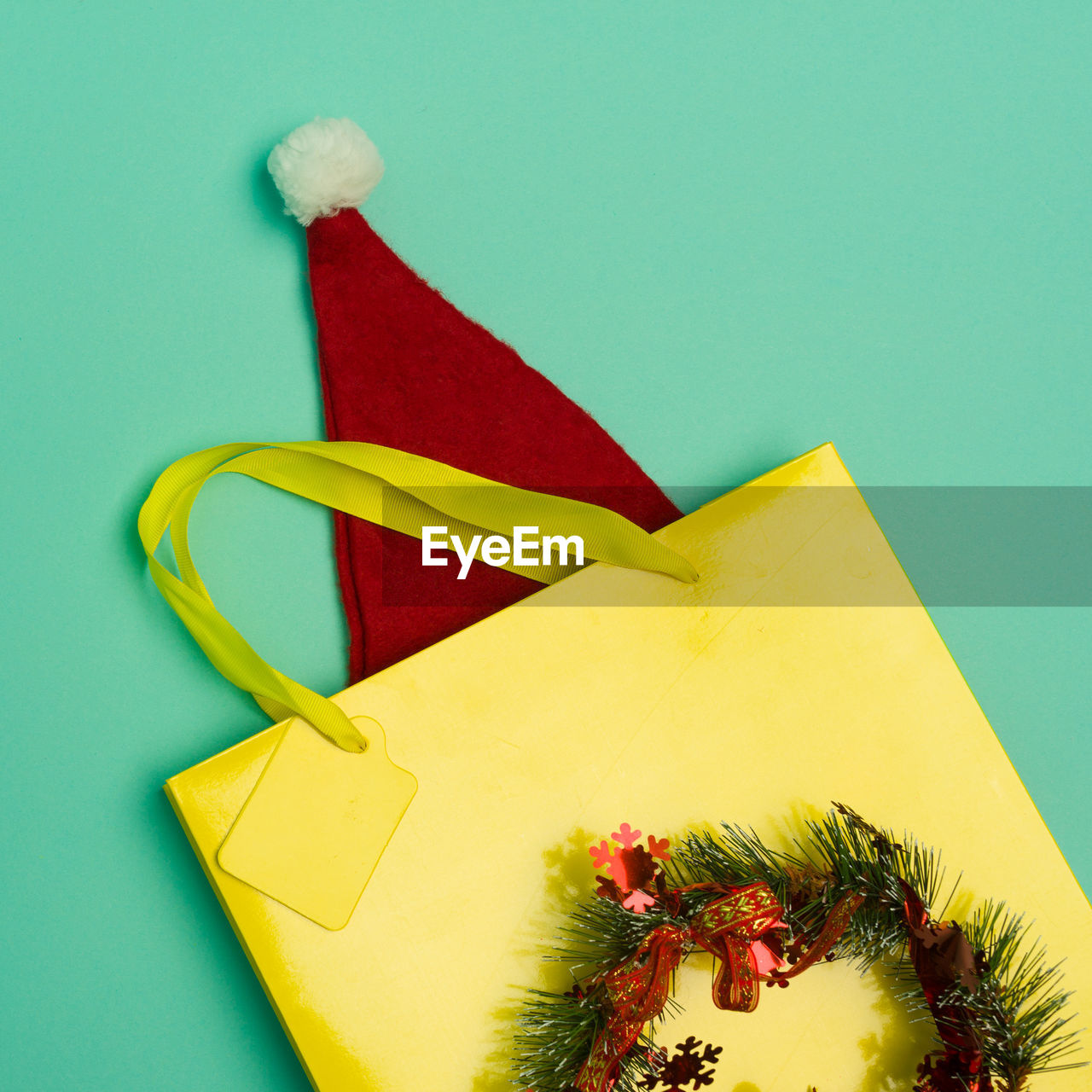 Top view yellow shopping bag with santa hat on the table with the holiday season