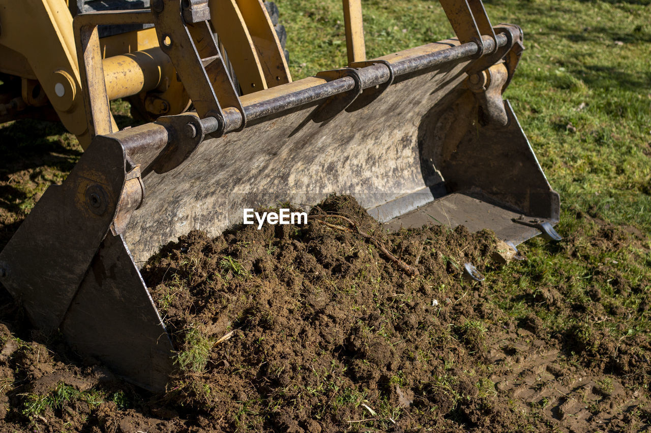 Clearing and leveling a private land plot. yellow excavator driving earth in a wide bucket