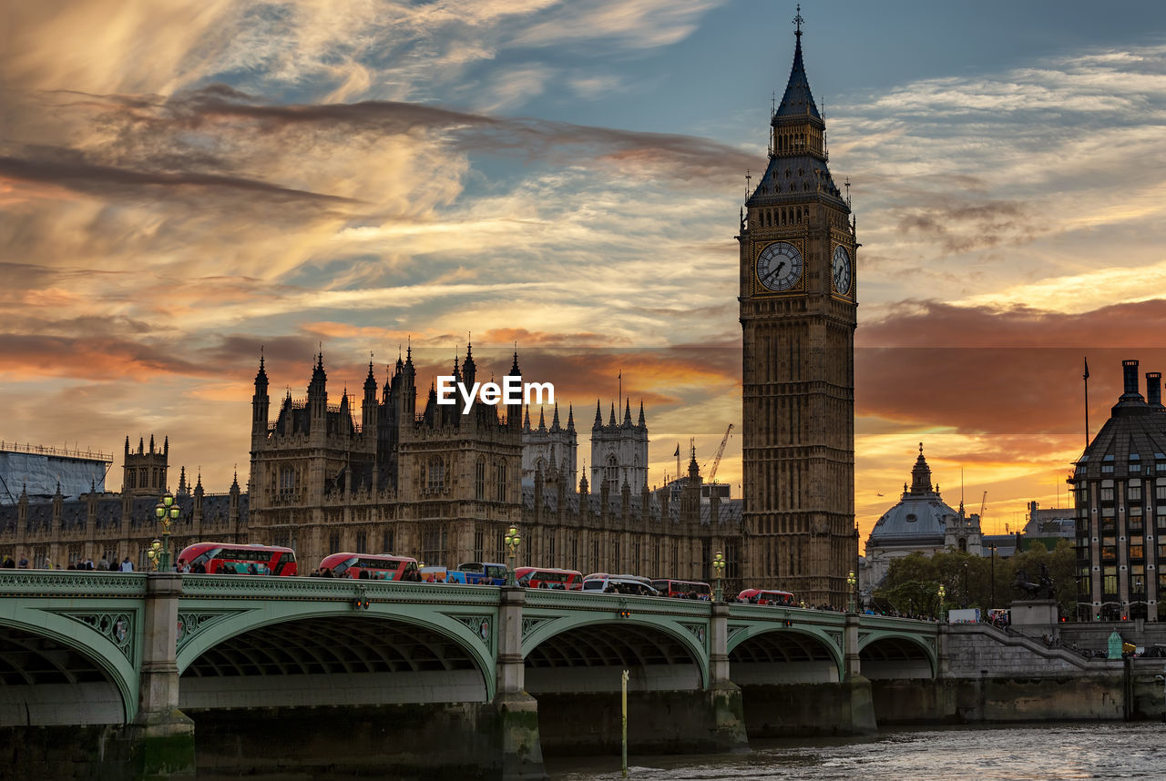 Westminster bridge over river against sky during sunset