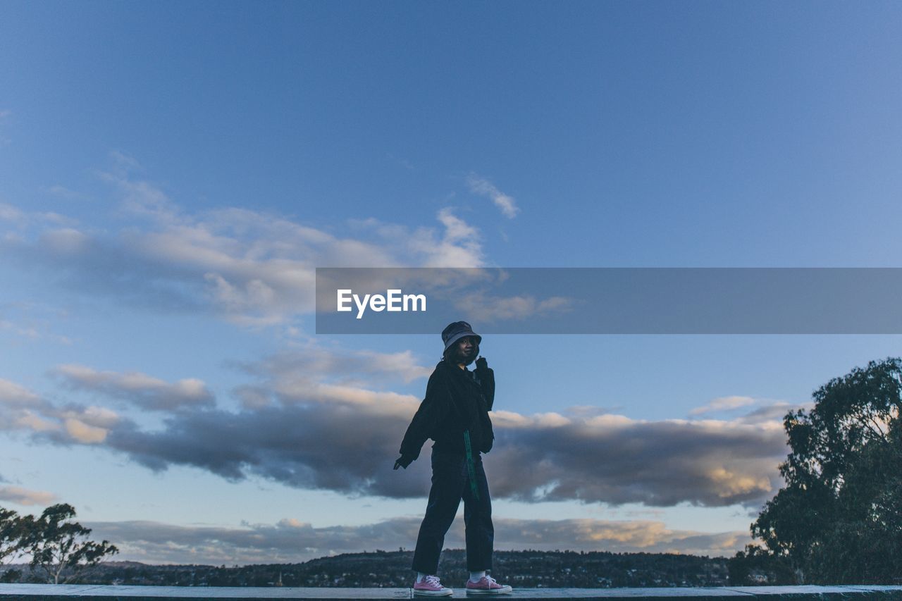 Woman standing on wall against sky