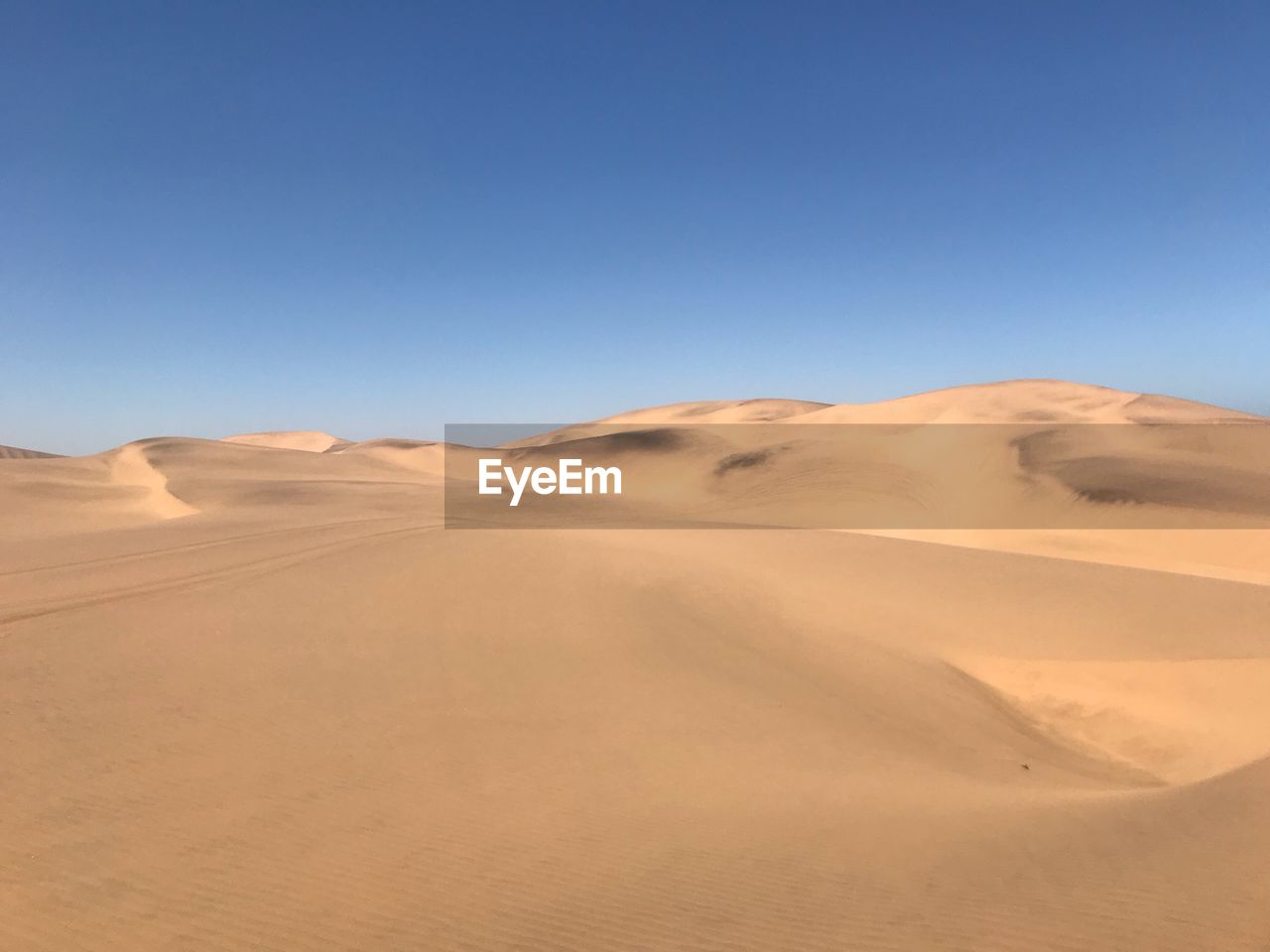 Scenic view of desert against clear blue sky