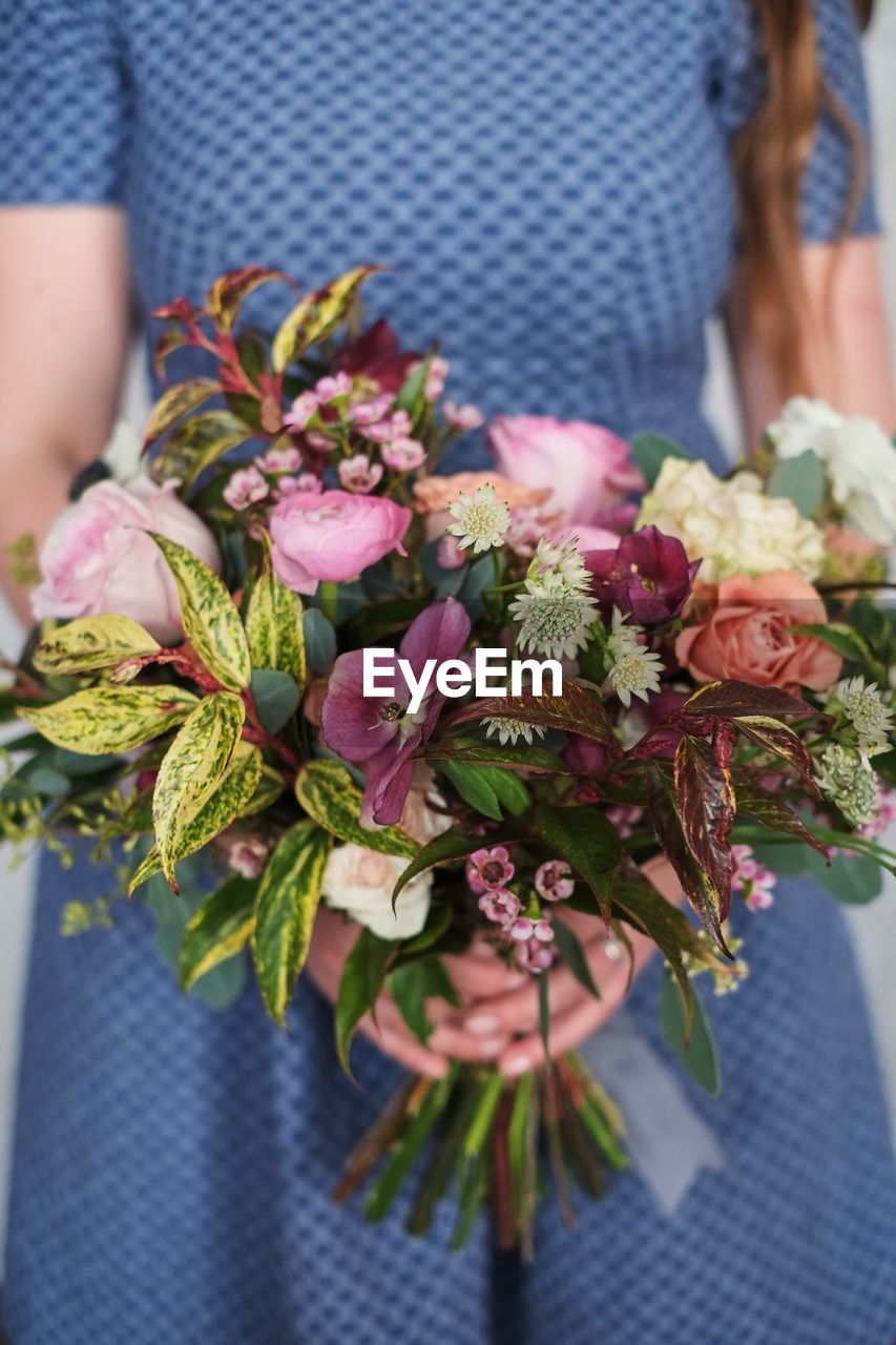 Midsection of woman holding flower bouquet