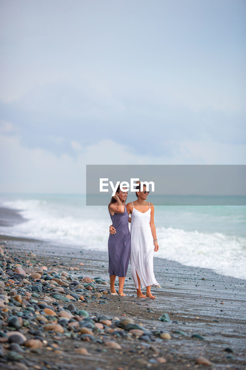 Full length of women standing on beach against sky