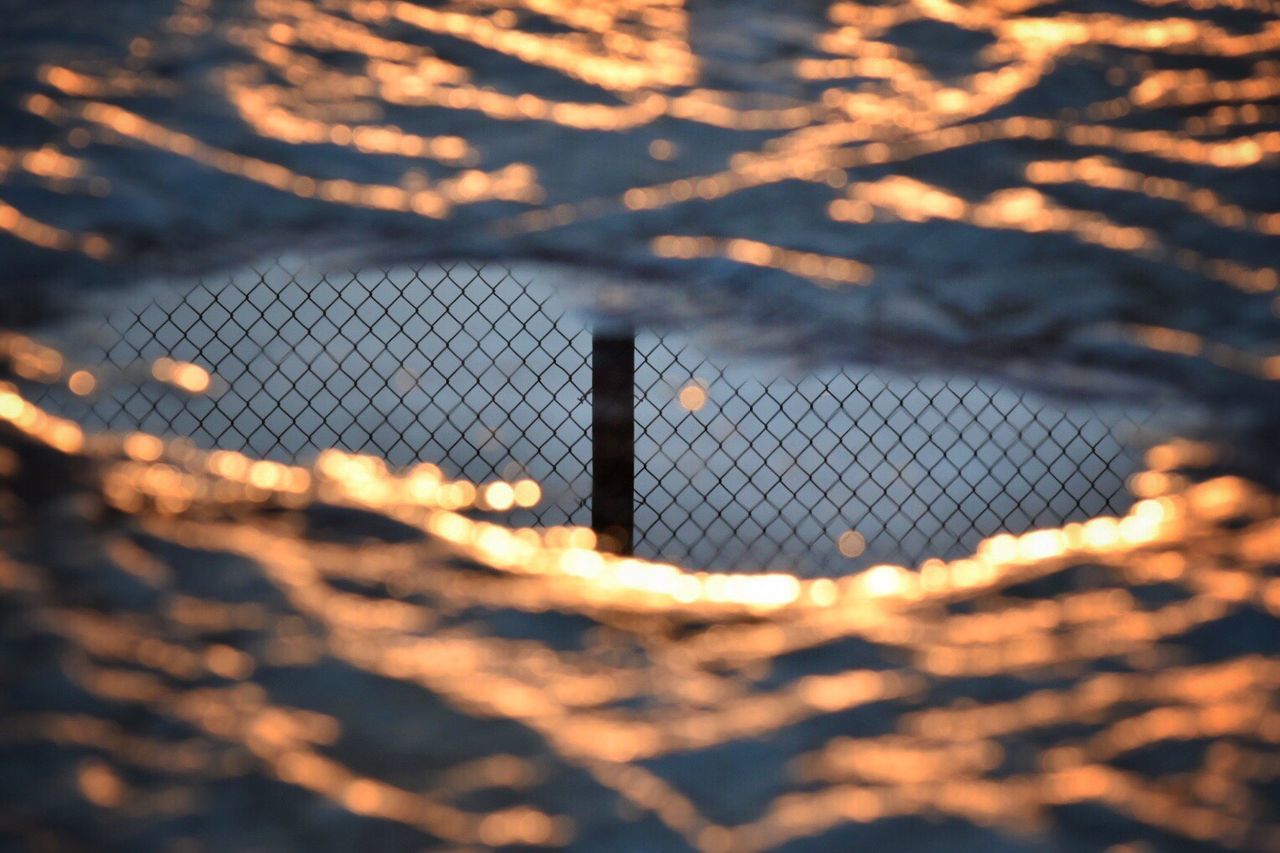 CLOSE-UP OF CHAINLINK FENCE DURING SUNSET