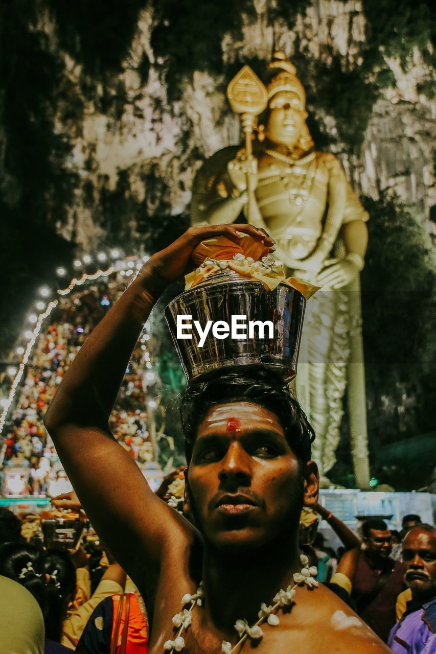 Man standing against statue during traditional ceremony