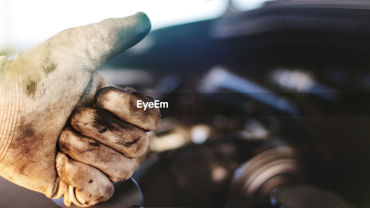 Cropped image of mechanic gesturing thumbs up against car engine