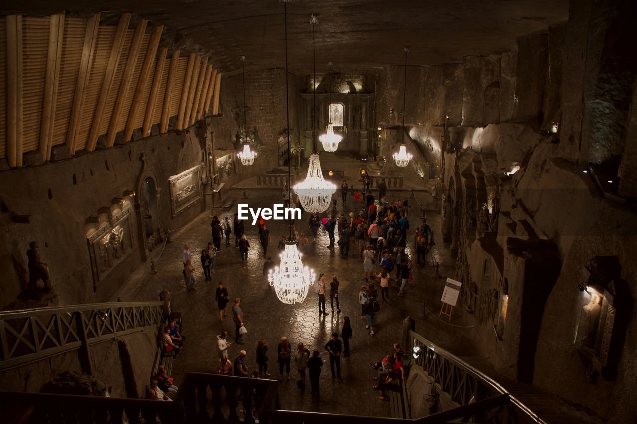 HIGH ANGLE VIEW OF PEOPLE IN ILLUMINATED UNDERGROUND WALKWAY