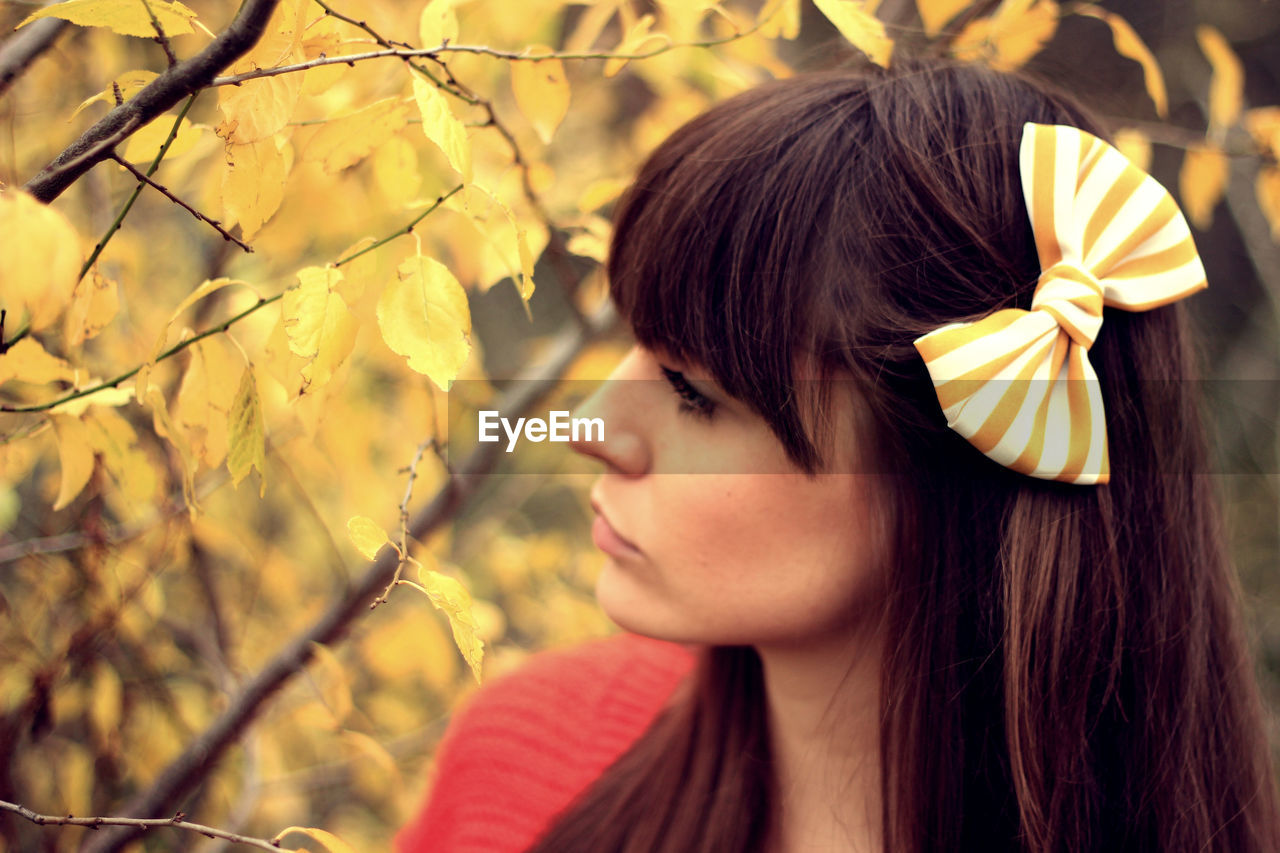 Woman wearing hair bow against tree