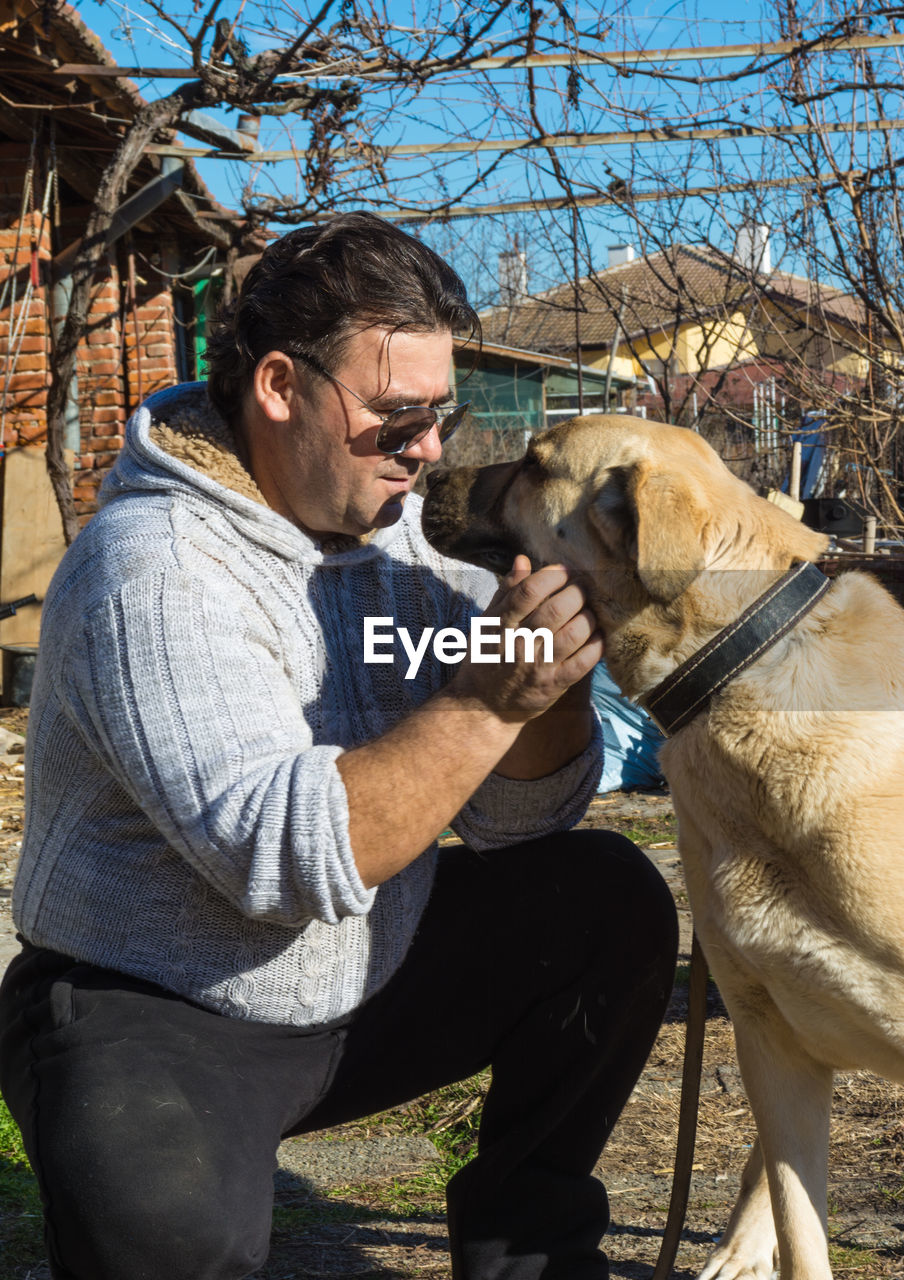 Man petting dog on field during sunny day