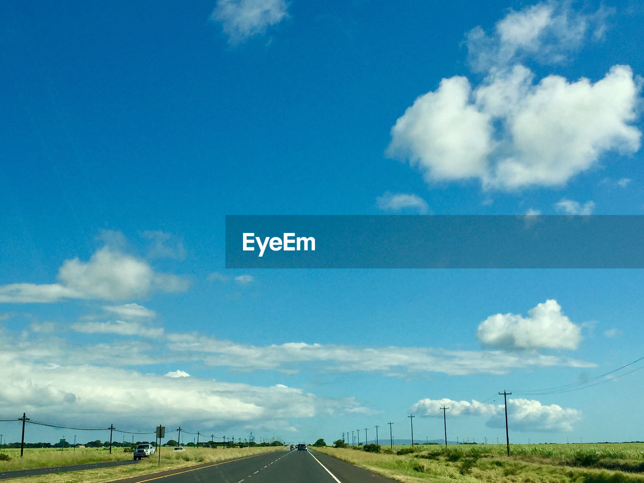 ROAD PASSING THROUGH FIELD AGAINST SKY