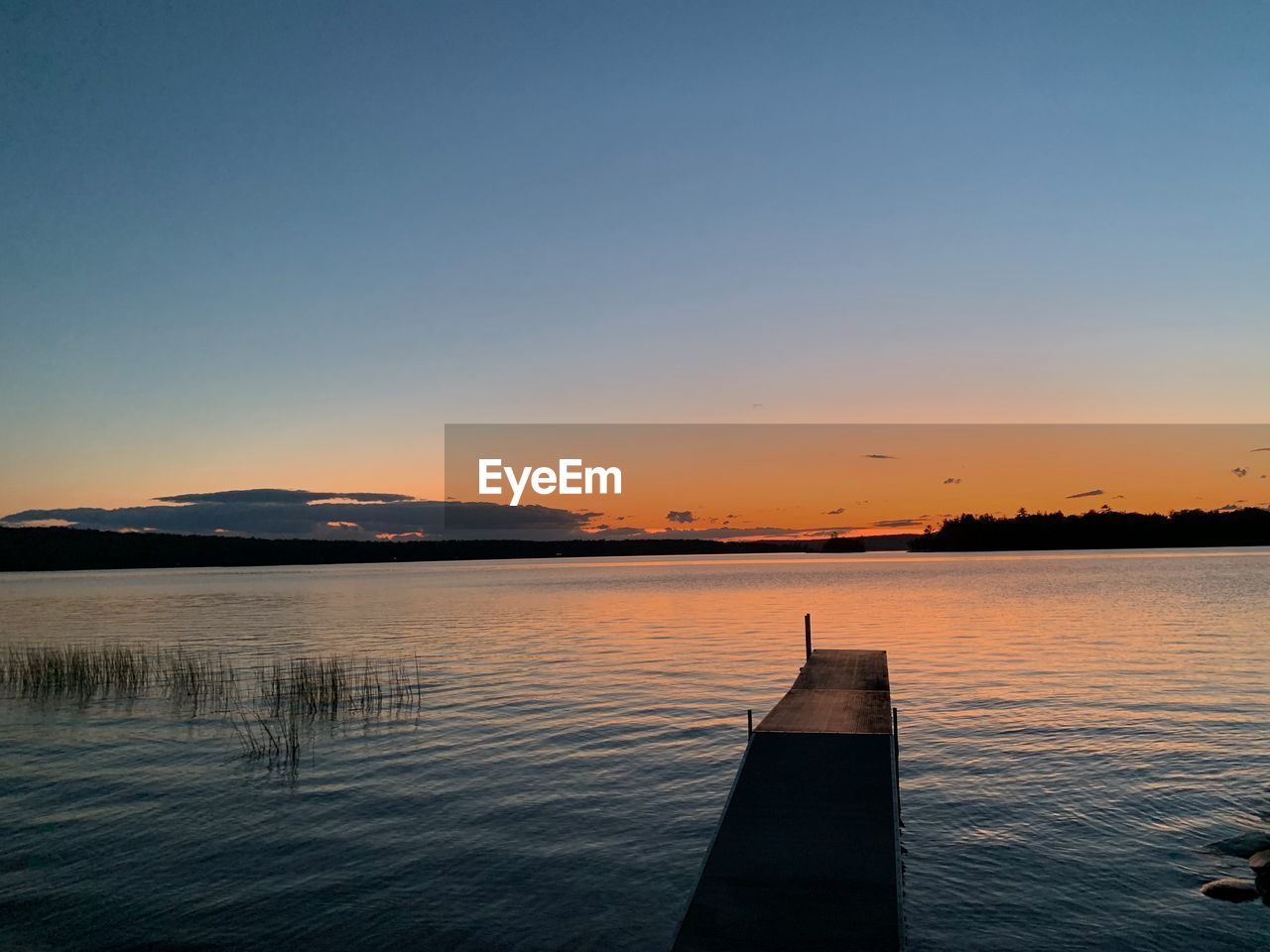 SCENIC VIEW OF LAKE AGAINST CLEAR SKY AT SUNSET